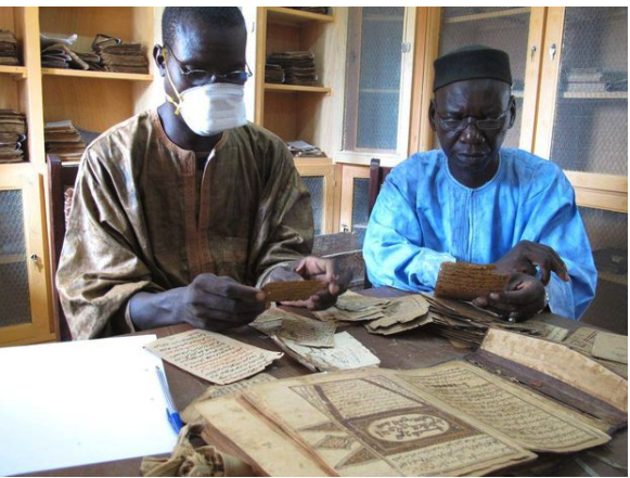 Two archivists, Aboubakar Yaro (left) and Alphamoye Djeite (right), study ancient manuscripts in a library in the Malian town of Djenne.