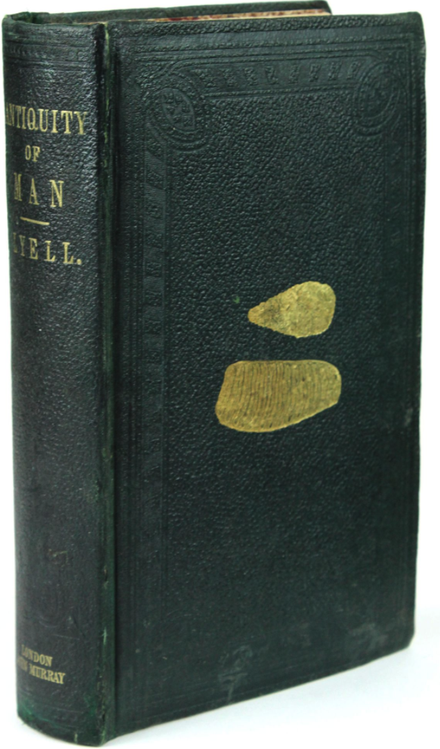 The deceptively simple gold stamping on the upper cover are a paleolithic handaxe above a mastodon tooth. It was the discovery by Boucher de Perthes of stone tools in proximity and in the same geological strata as the bones of extinct animals that initiated the research leading to the acceptance by Lyell and other establishment scientists of the antiquity of man.