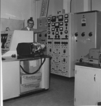 Brian Jeffrey getting ready to power up the machine from the main power panel. Note the Creed teleprinter on the console at the left of the picture. Circa 1958.