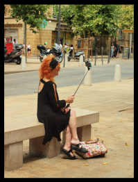 A woman taking a selfie with a selfie stick extension for her phone.