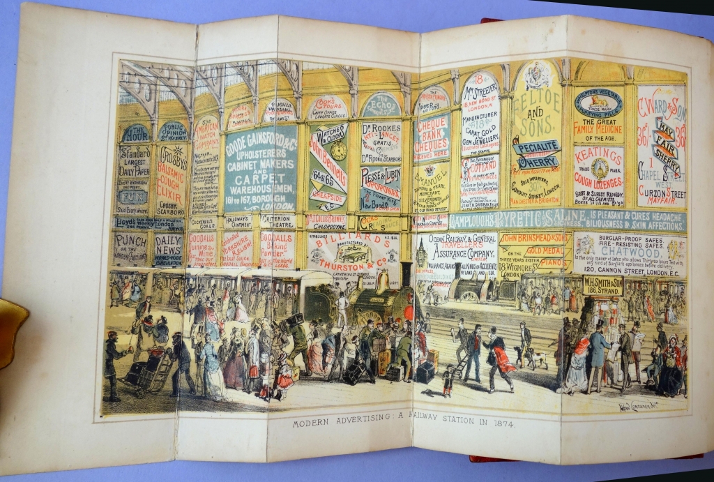 "Modern Advertising: A Railway Station in 1874" The W.H. Smith bookstall is in the lower right.